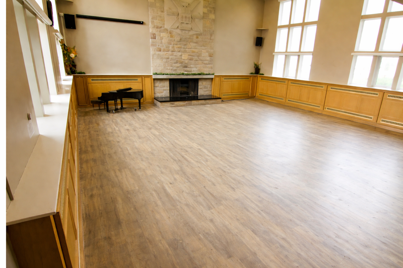 The Hall interior — hardwood floors, stone fireplace and grand piano