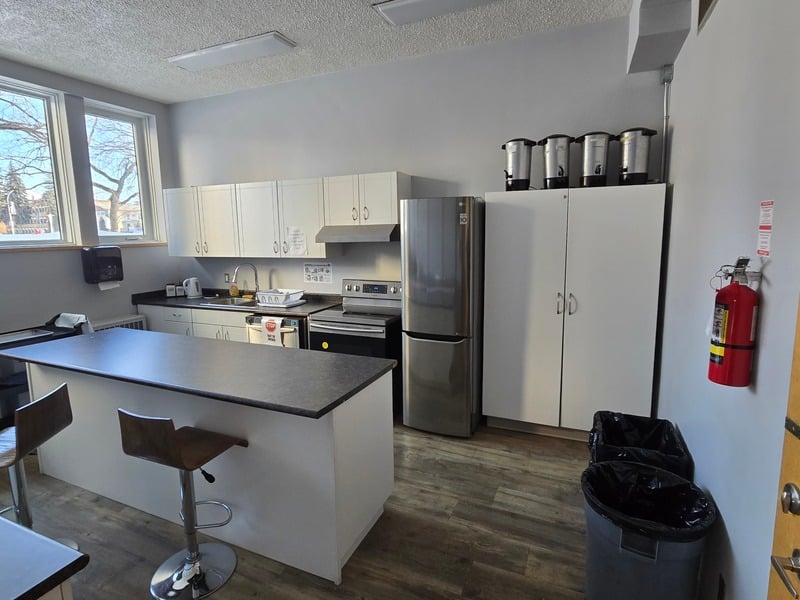 Full kitchen with stainless fridge, stove, island and coffee urns